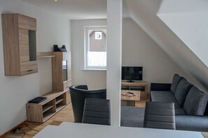A modern living space with a TV, sofa, and wooden entertainment unit.