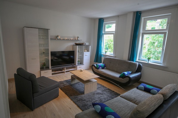 A living room with a TV, sofa, and coffee table.