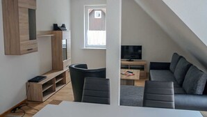 A modern living space with a TV, sofa, and wooden entertainment unit. - Apartment Lerbachtal - Apartment Lerbachtal L3 2-6 persons (Osterode am Harz)