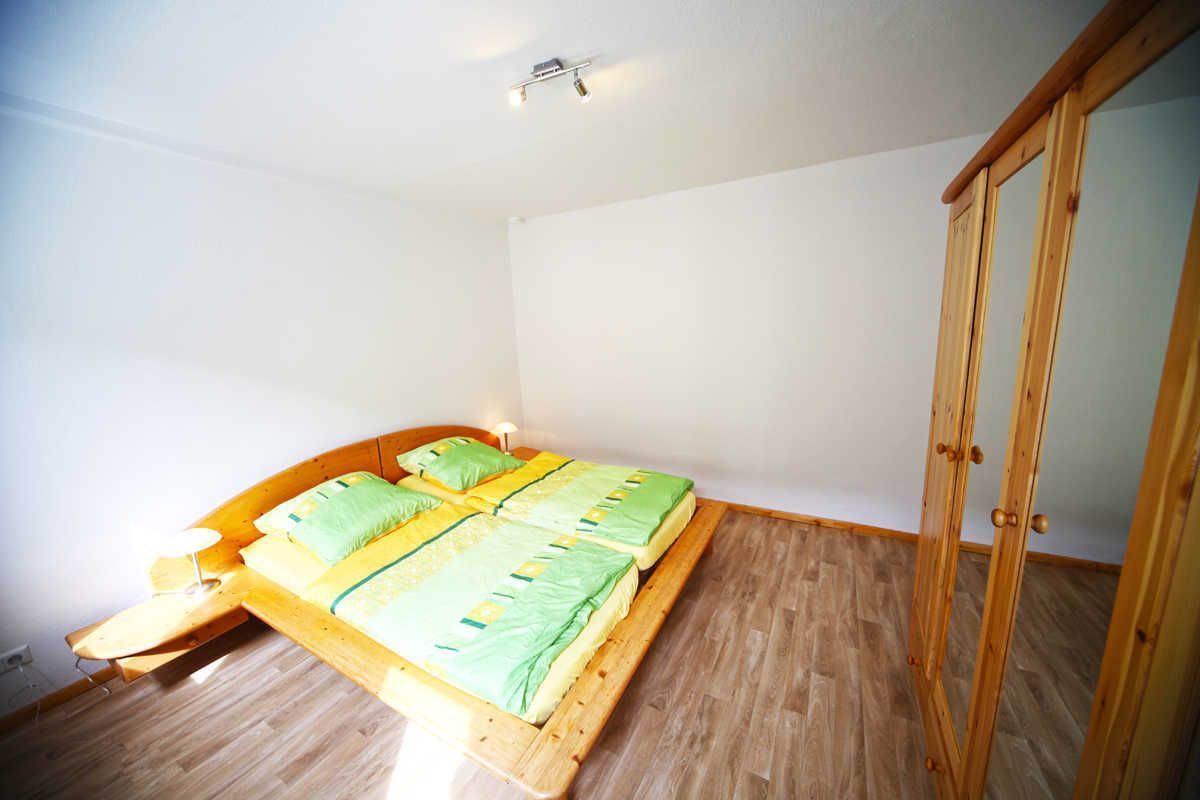 A bedroom with a wooden bed, a nightstand, and a wardrobe.