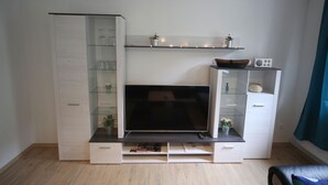 A modern living room with a flat-screen TV, built-in shelving, and a coffee table. - Apartment Lerbachtal - Apartment Lerbachtal L3 2-6 persons (Osterode am Harz)