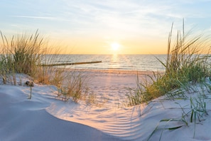 A beach scene with sand dunes, grasses, and a wooden pier extending into the water. - Käptn Brass App 27 - Käpt`n Brass App.27 (Dierhagen)