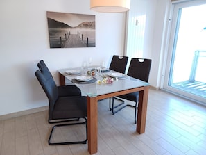 A dining area with a glass table, black chairs, and a painting on the wall. - Käptn Brass App 27 - Käpt`n Brass App.27 (Dierhagen)