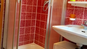 A bathroom with a glass-enclosed shower, a white sink, and a mirror above it. - Fewo Nordlichstraße - Fewo Nordlichtstraße (Norden)
