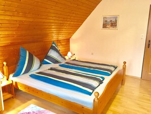 Una cama de madera con ropa de cama a rayas en una habitación con paredes de madera y techo inclinado.