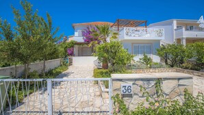 A modern villa with a stone pathway leading to the entrance, surrounded by lush greenery and a clear blue sky. - 3 bedroom awesome apartment in Rogoznica (Rogoznica)