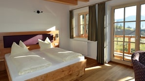 Una habitación con una cama de madera, una ventana con cortinas y vistas al exterior.