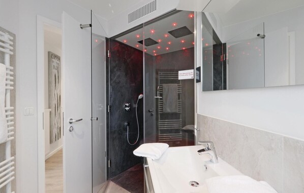 Une salle de bain moderne avec une douche à parois de verre, un lavabo blanc et un porte-serviettes.