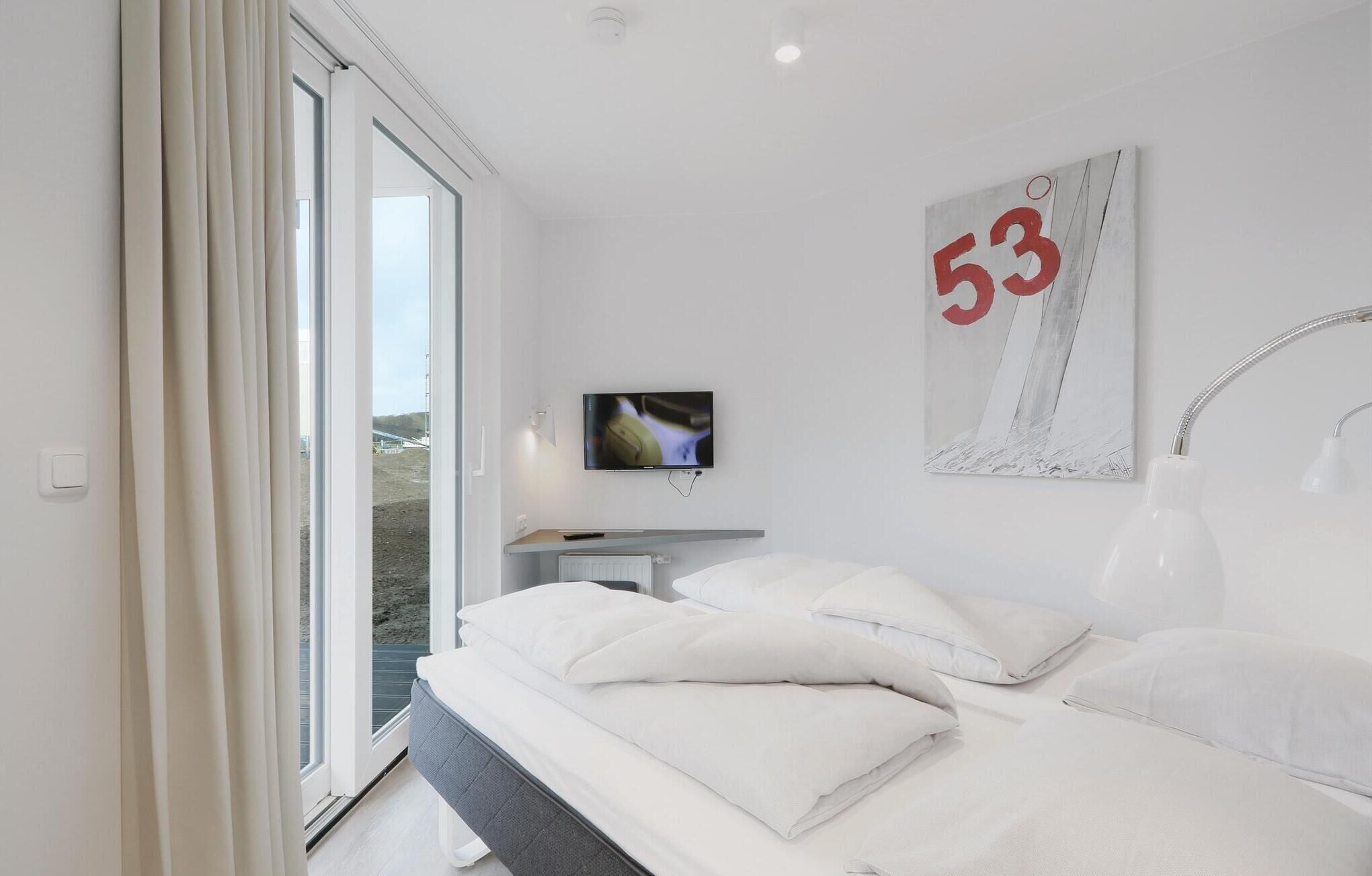 Ein modernes Hotelzimmer mit einem großen Bett, einem Fernseher und Blick ins Freie.