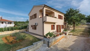 A two-story house with a balcony, surrounded by a garden and trees. - Amazing apartment in Radmani with WiFi (Radmani)