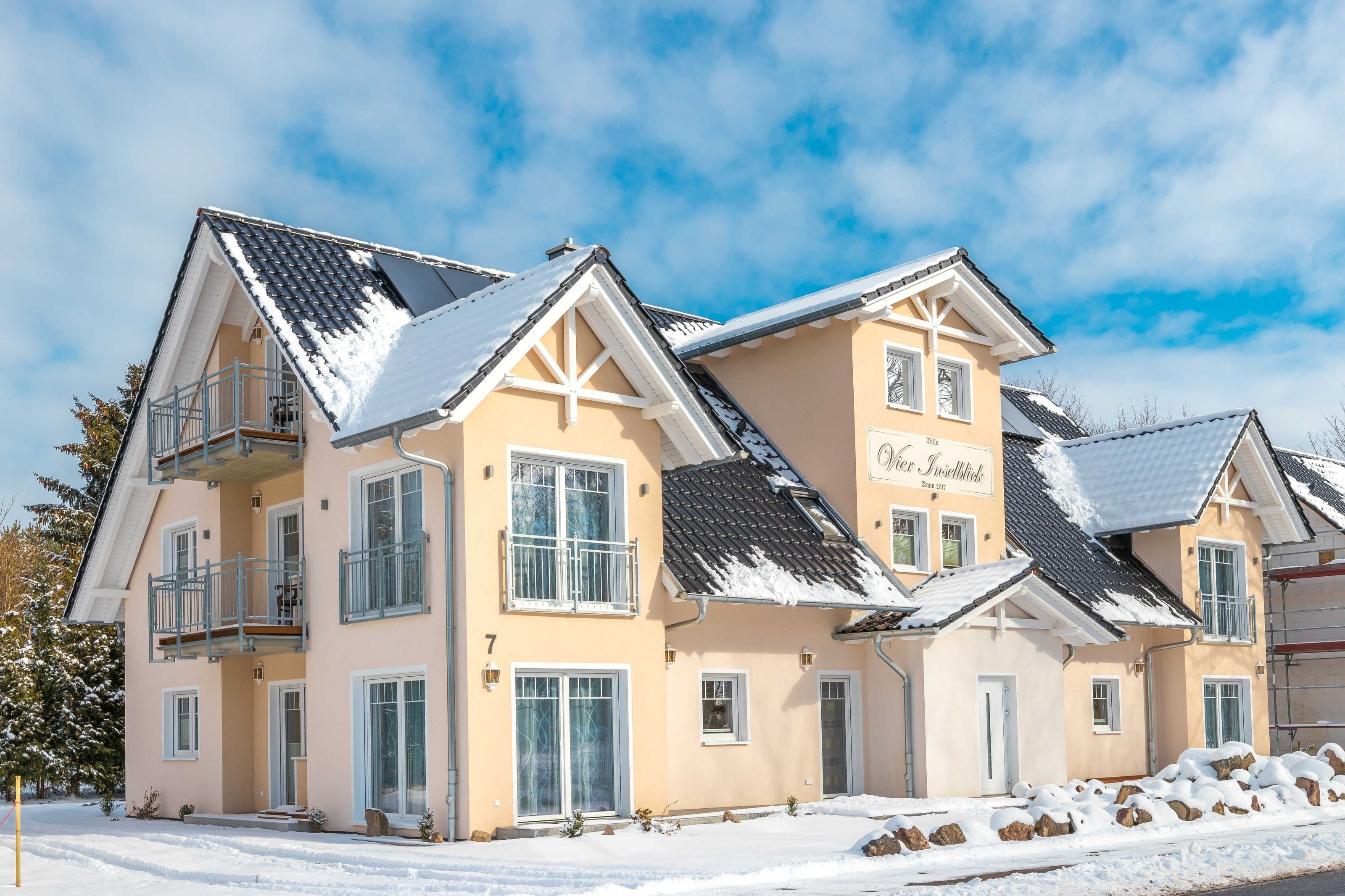 A multi-story hotel with a balcony, large windows, and a snow-covered roof.