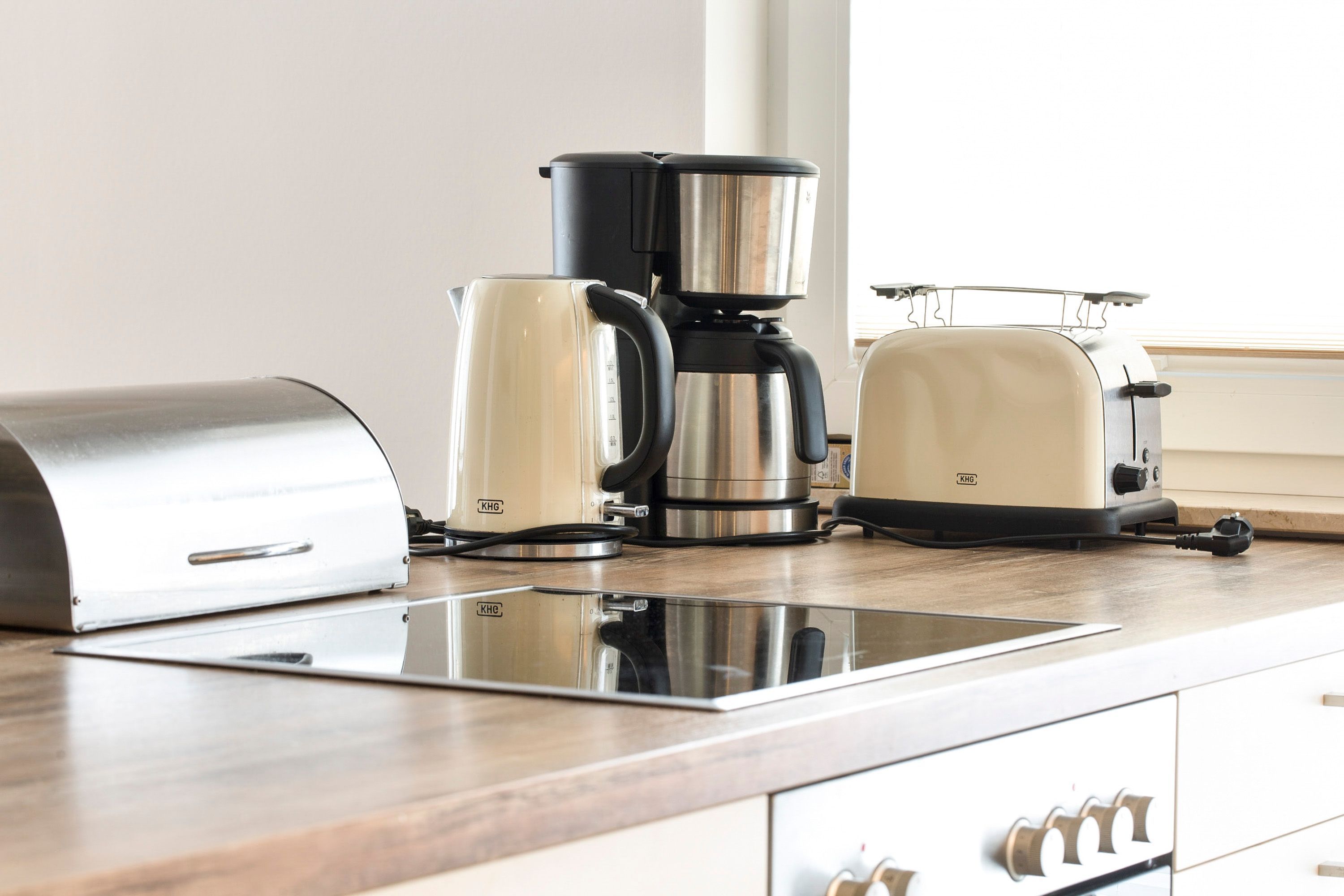 Eine Küche mit einer Edelstahl-Kaffeemaschine, einem Wasserkocher und einem Toaster auf der Arbeitsfläche.