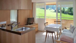 Eine kompakte Küche mit Spüle, Herd und einem Essbereich mit Tisch und Stühlen.
