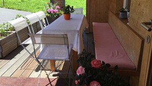 Eine Holzterrasse mit einer Bank, einem Tisch und Stühlen.