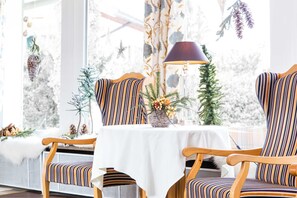 Ein Essbereich mit gestreiften Stühlen, einem Tisch mit weißer Tischdecke und einer Lampe.