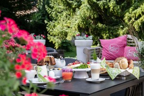 Ein Tisch im Freien mit Frühstücksgegenständen, einer Karaffe und einem Glas Saft.