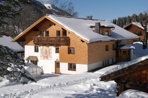 Una cabaña de madera con balcón, rodeada de montañas nevadas.