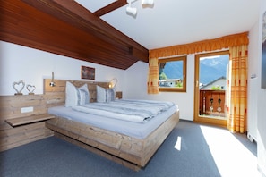 A bedroom with a wooden bed, a nightstand, a headboard with a mirror, and a window with curtains.