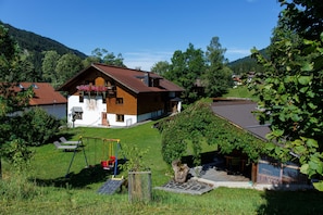 A house with a sloped roof, a swing set, and a small garden.