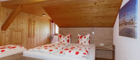 Un dormitorio de cabaña de madera con una cama, dos mesitas de noche, una lámpara de pared y un cuadro.
