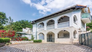 Un edificio de dos plantas con fachada de piedra, varios balcones y un patio empedrado.