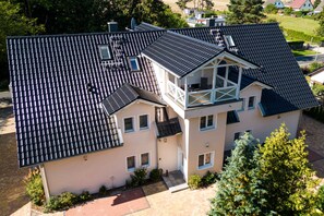 A two-story house with a sloped roof, multiple windows, and a small balcony. - Apartment Ruden - Villa Vier Inselblick (Kröslin OT Freest)