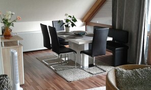 Un comedor moderno con una mesa blanca, sillas negras y una planta en maceta.