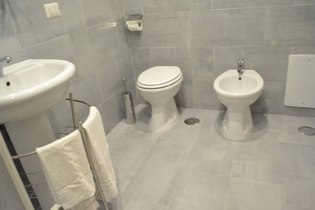 Un baño con lavamanos, inodoro, bidé y un perchero para toallas.
