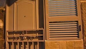 A door with a metal grille and a window with horizontal blinds. - Bassetto 013 (Naples)