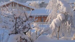 A snow-covered landscape with a building that has a sloped roof and a visible window.