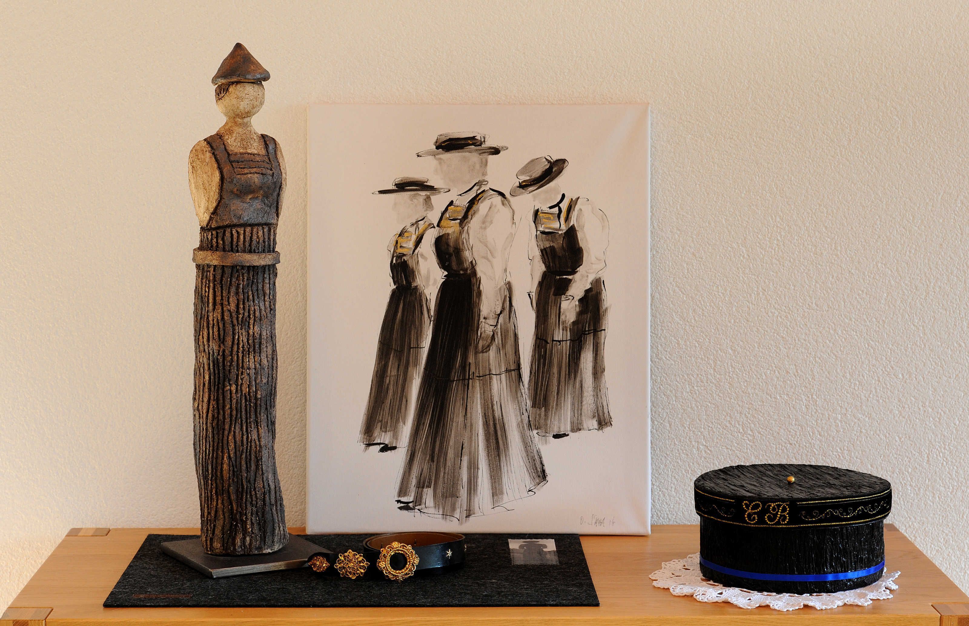 Une sculpture, un tableau et un chapeau sur une table.