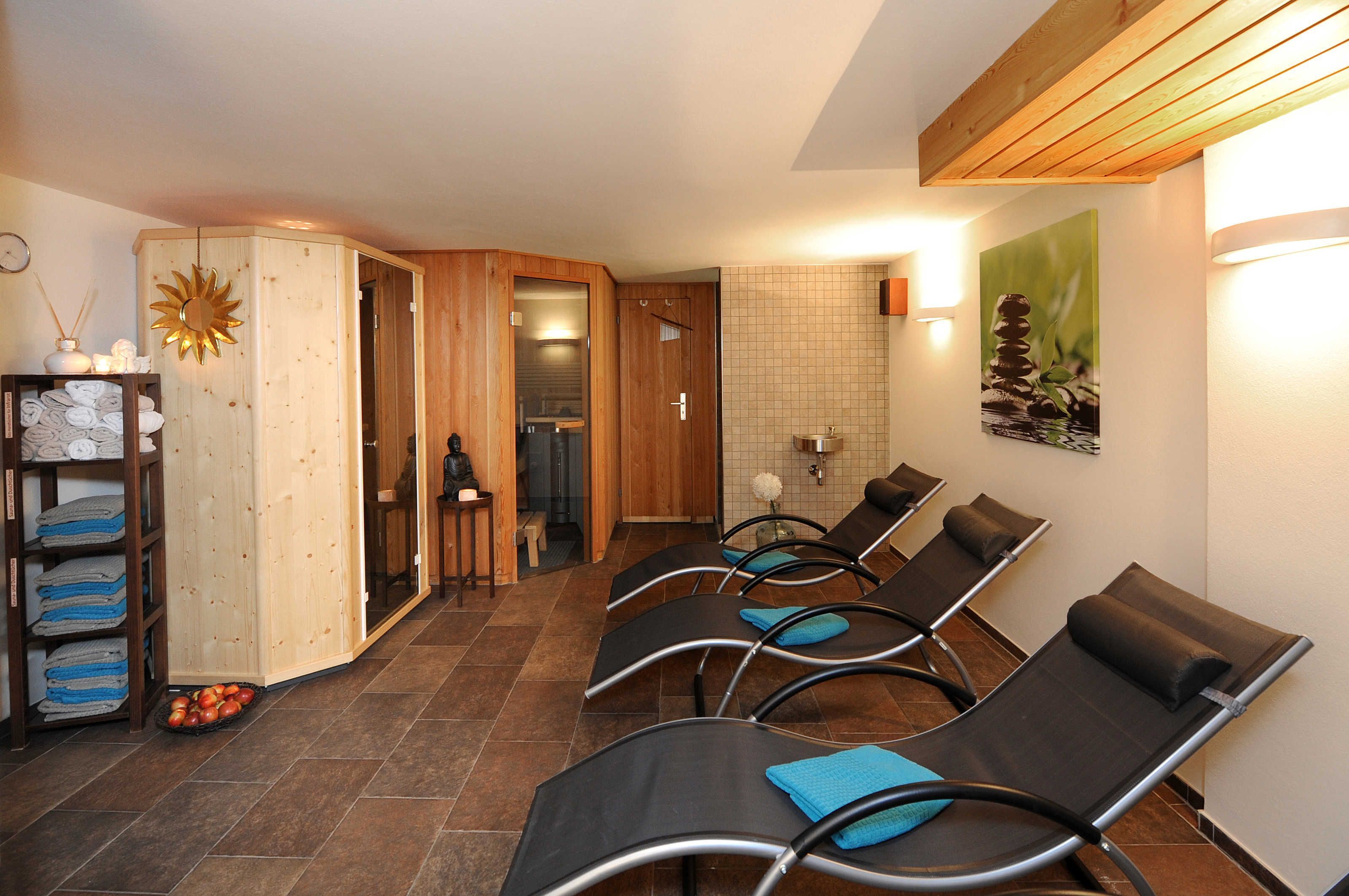 Un cuarto de spa con paredes de madera, un adorno de sol, un perchero y una zona de espera con sillas.
