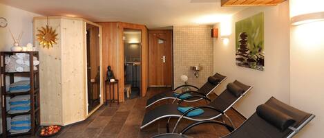 Un cuarto de spa con paredes de madera, un adorno de sol, un perchero y una zona de espera con sillas.