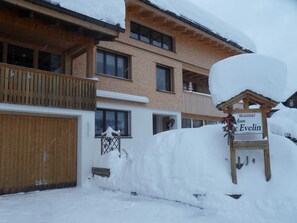 Una cabaña de madera con un letrero que dice 'Wohlfahrt Haus Evelin', rodeada de nieve.