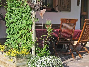 Una silla de madera, una decoración con forma de corazón y una jardinera de madera con plantas.