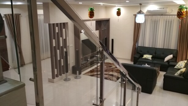A modern living room with a staircase, a black sofa set, and decorative pineapples.