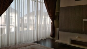 A hotel room with a large window, a bed, and a TV on a stand.