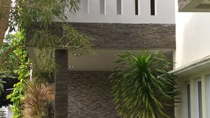A modern building with a stone facade, a balcony, and a well-maintained garden with various plants and a seating area.