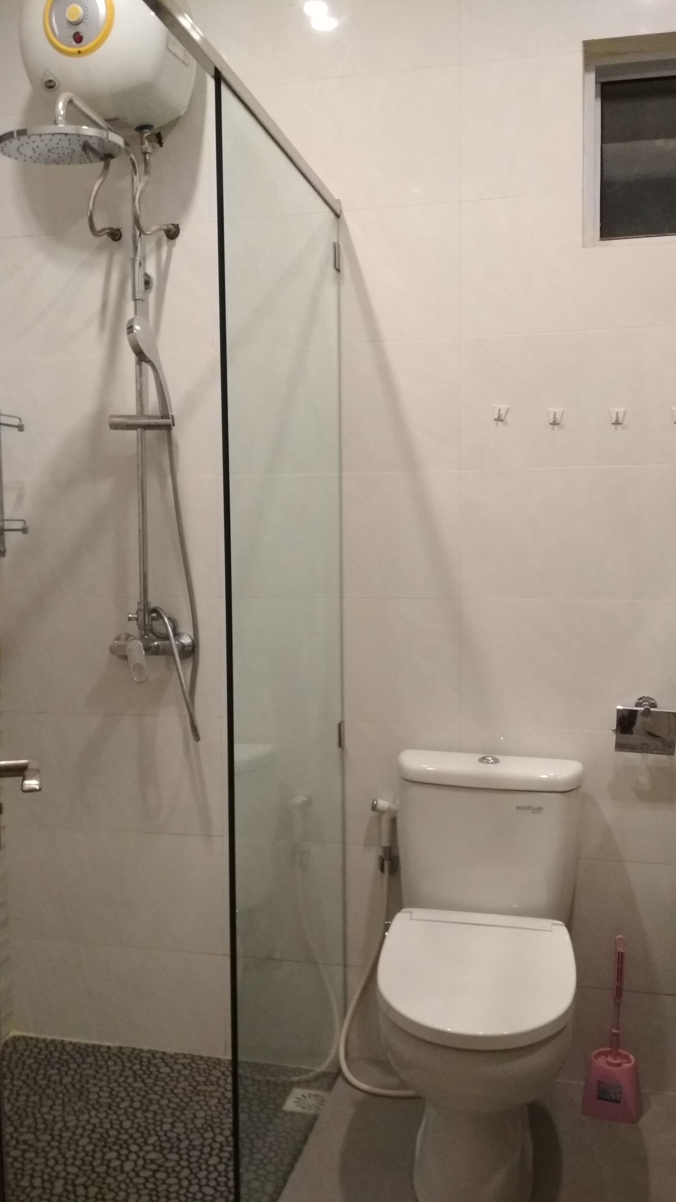 A modern bathroom with a glass shower enclosure, a white toilet, and a handheld showerhead.