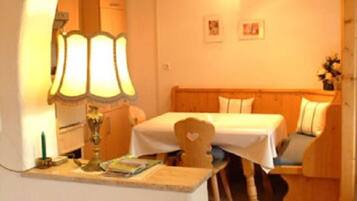 A small room with a wooden bed, a table, a lamp, and a chair.