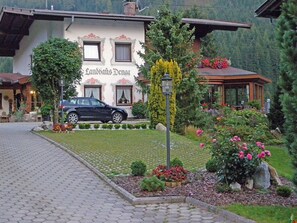 A building with a sign reading 'Landhaus Denaa,' a paved driveway, and a car parked in front.
