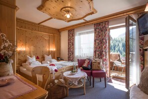 A wooden room with a bed, a table, a chair, and a television.