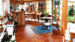 Un comedor con una mesa de madera, sillas y suelo de ladrillo.