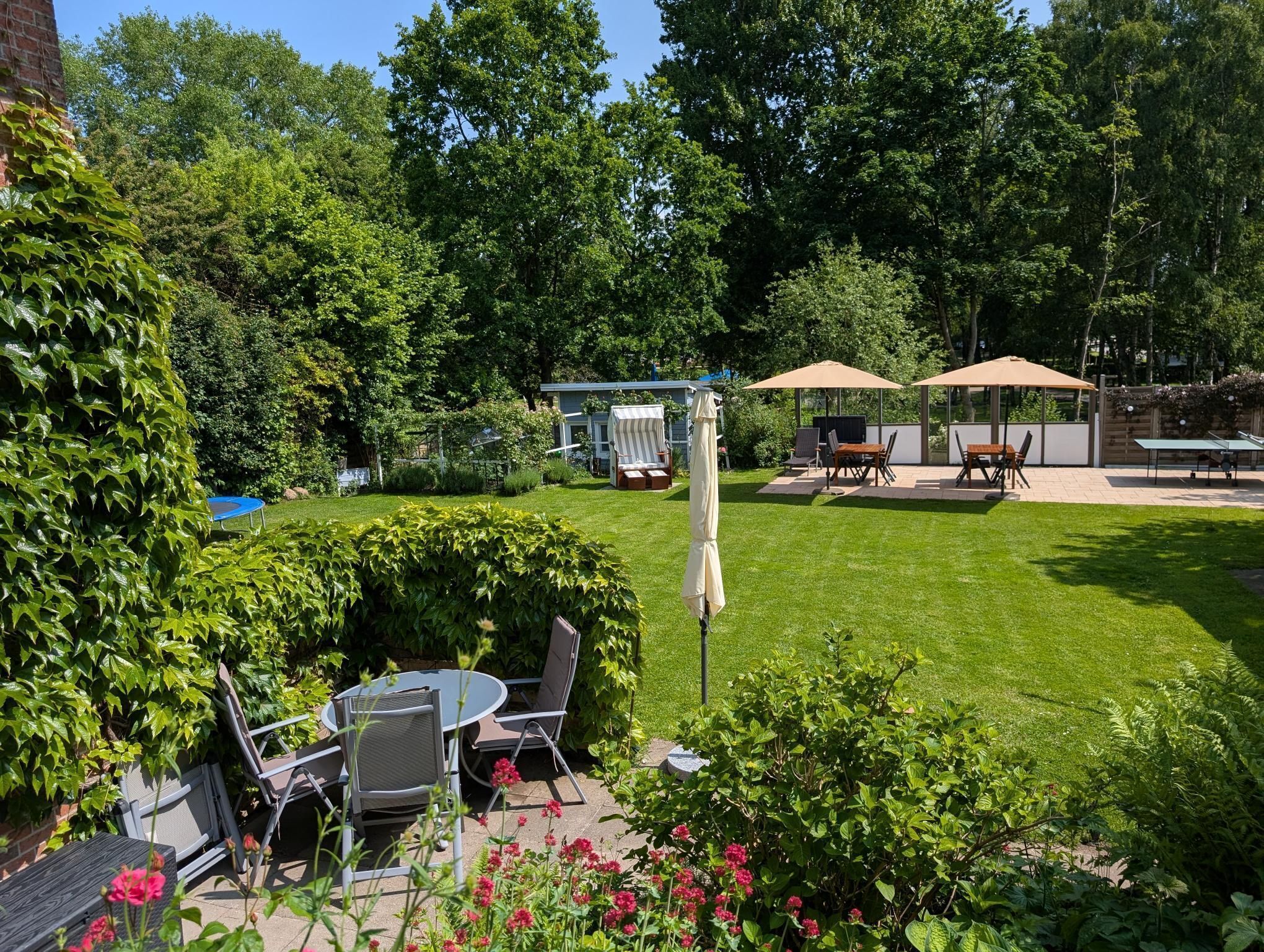 Ein Garten mit einer Terrassenfläche, Sitzgelegenheiten im Freien und einem kleinen Gartenhaus.