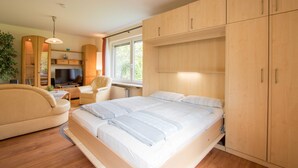 Ein modernes Schlafzimmer mit einem großen Bett, einem Holzschrank und einem Fernseher in einer gemütlichen Ecke.