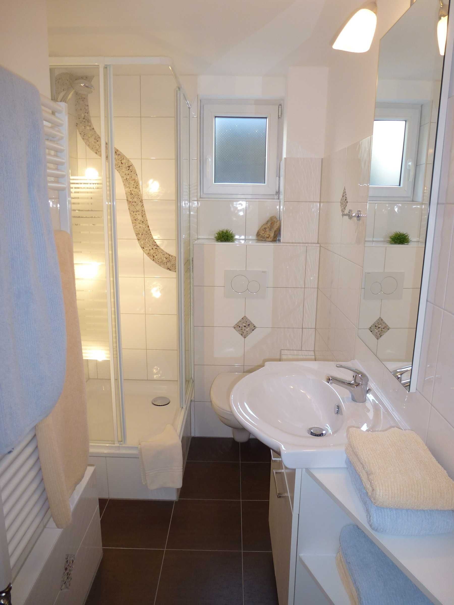 Ein modernes Badezimmer mit Duschkabine aus Glas, einem weißen Waschbecken und einem großen Spiegel.