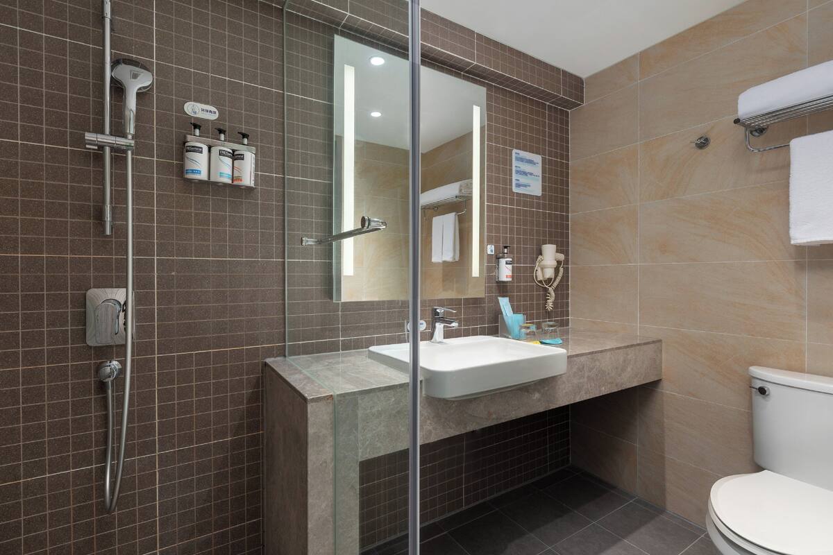 A modern bathroom with a glass-enclosed shower, a white sink, and a toilet.