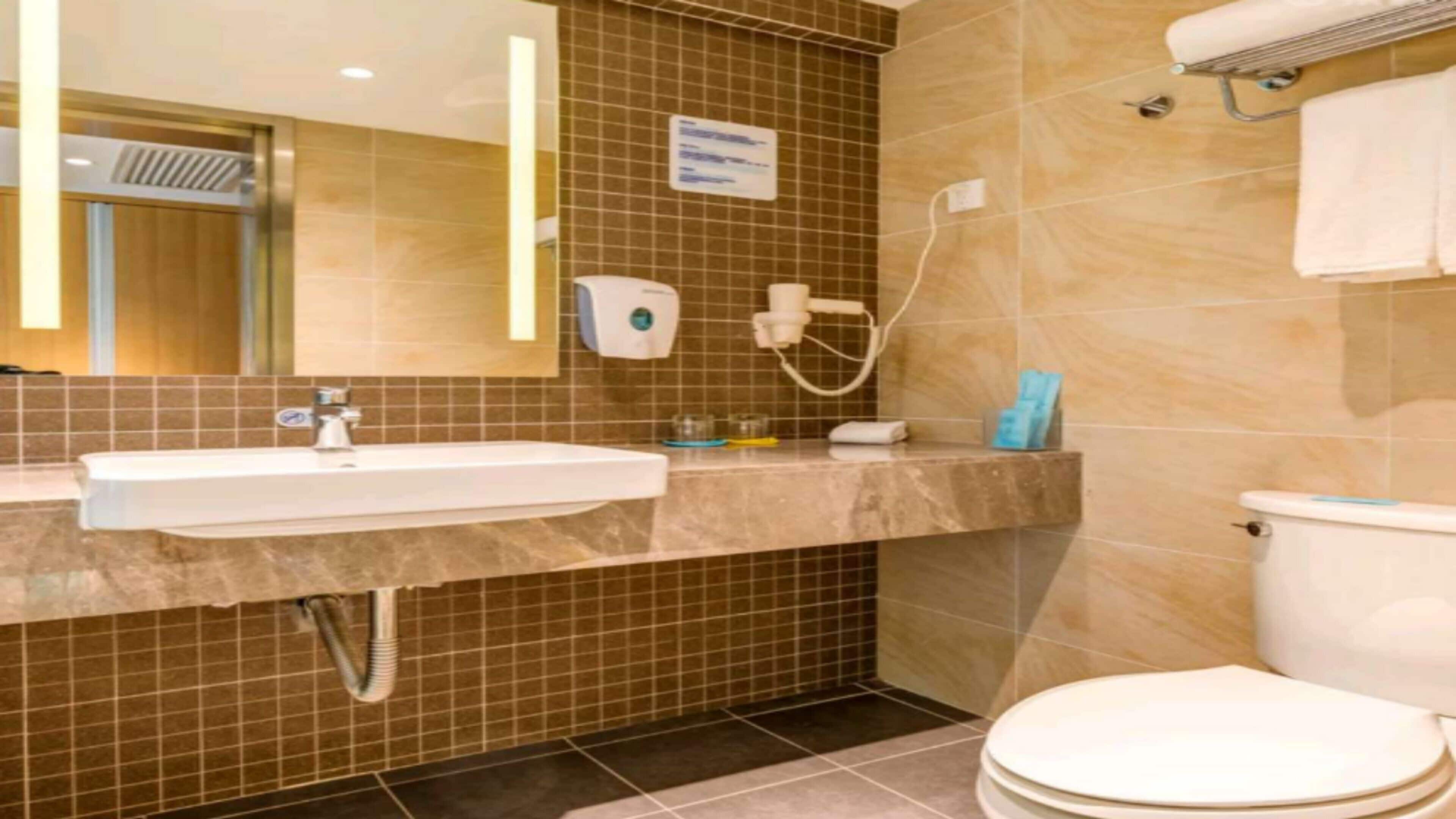 A bathroom with a sink, mirror, towel rack, and toilet.
