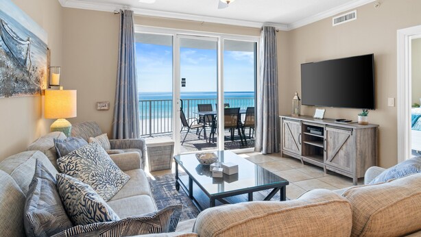 Een woonkamer met uitzicht op zee, een plafondventilator, een flatscreen televisie en een eethoek met buitenmeubilair.