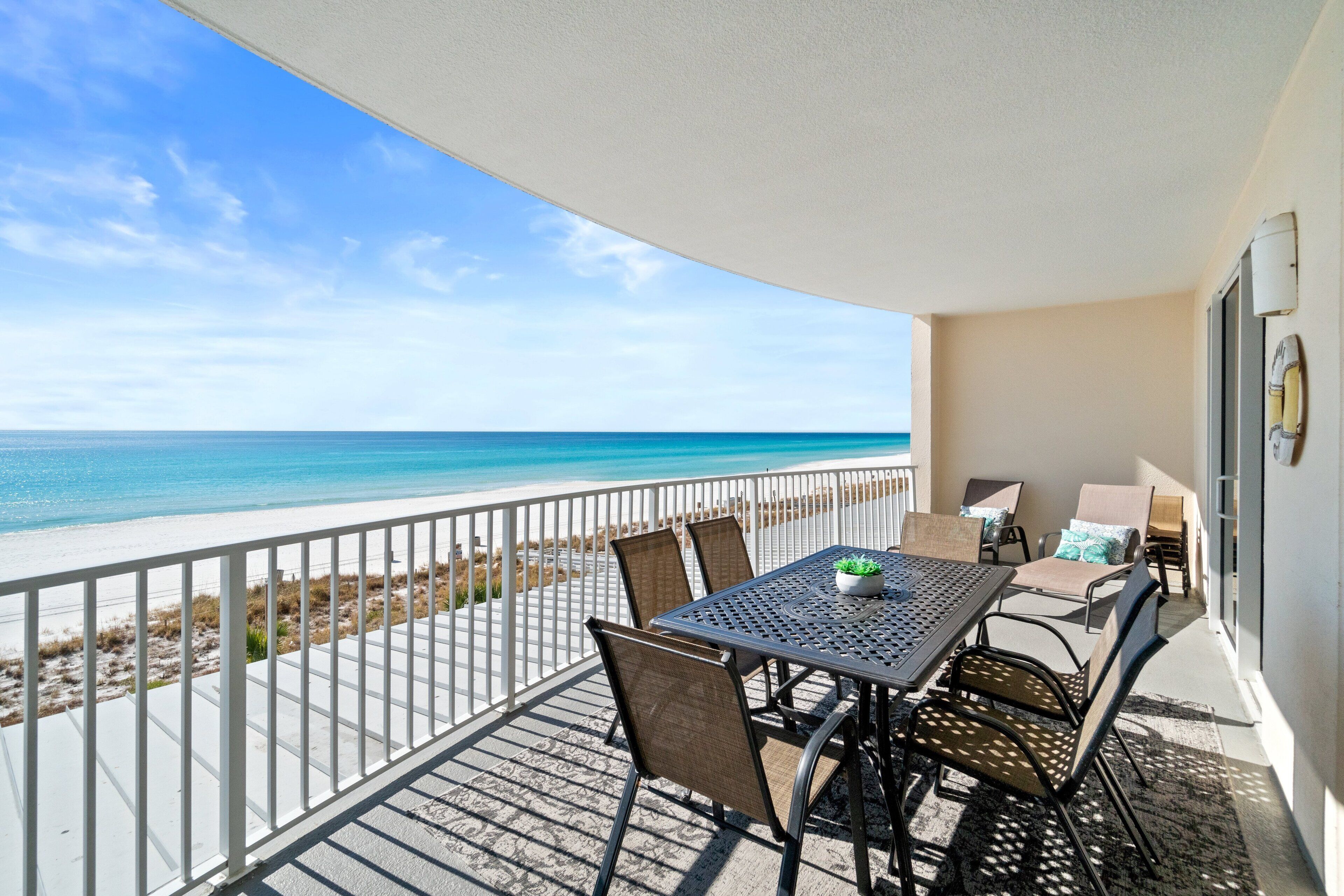 Ein Balkon mit Tisch und Stühlen mit Blick auf einen Strand.